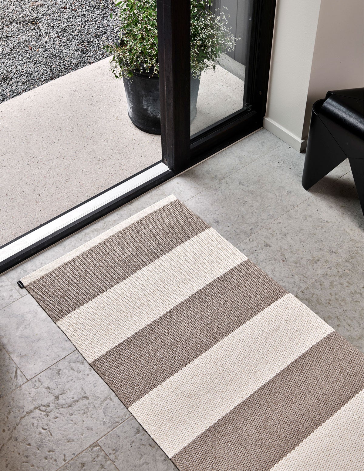 Bob Gångmatta i färgen Mud / Vanilla framför dörr