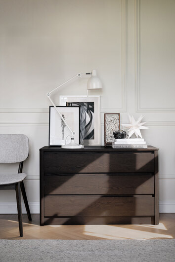 Melstone Byrå i brun ek dekorerad med en lampa, tavlor och böcker