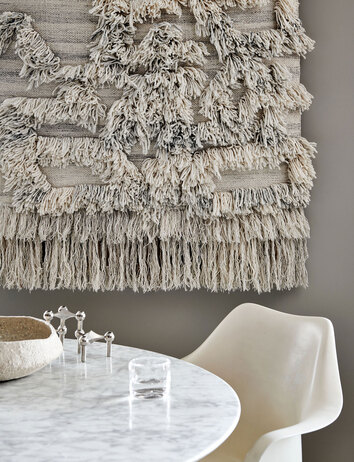 Rio Väggbonad i färgen Ivory/Melange hängande på vägg bakom ett runt matbord