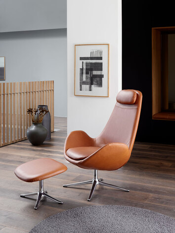 Ghost High Fåtölj med fotpall i lädret Nature Cognac med ben i polerad aluminium i ljust vardagsrum