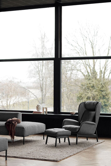 Padova Fåtölj och fotpall i lädret Nature Warm Stone Grey med svarta ben i modernt vardagsrum