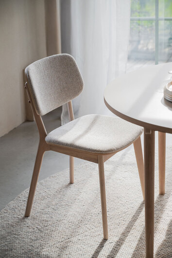 Barrett stol i vitpigmenterad ek med ljusbeige tyg på solig matplats