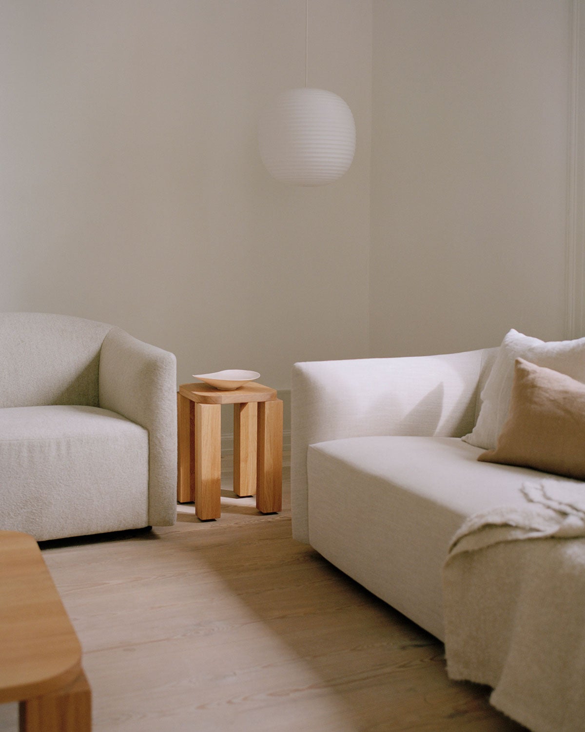 Atlas Pall Naturoljad Ek bredvid en soffa i ljust tyg