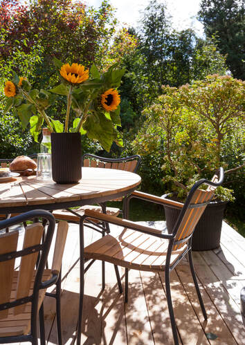 Ellen Trädgårdsstol och Trädgårdsbord på trädäck i solen med vackra solrosor i en vas