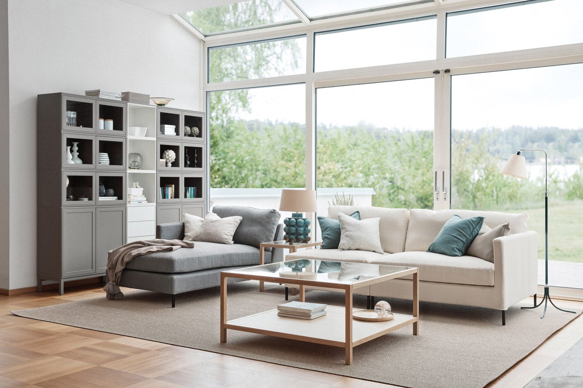 2000 Soffbord intill soffgrupp i ljust, öppet vardagsrum med stora fönster