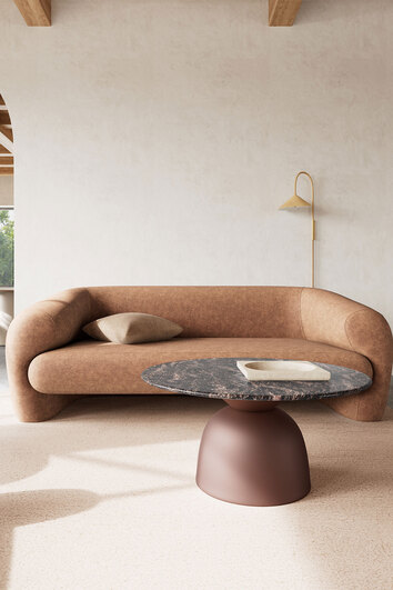 Ferrol soffbord i grå marmor med bronsfärgad stålfot i vardagsrumsmiljö med soffa. 