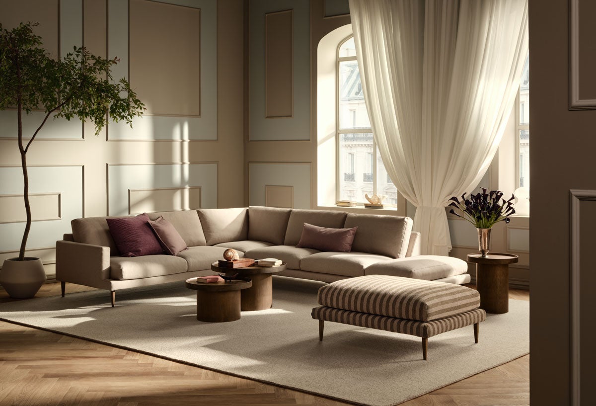 Veneda Hörnsoffa 6-sits med öppet avslut till höger i ett beige tyg. Hörnsoffan står i ett dunkelt vardagsrum med modern inredning.