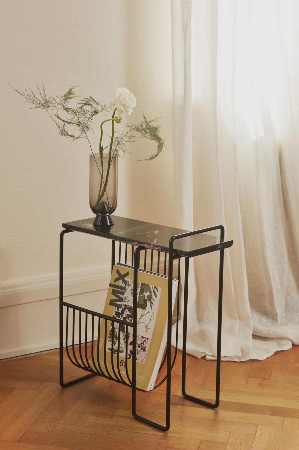 Sino Tidningsställ Svart Marmor med ett magasin och en vacker vas med blommor i