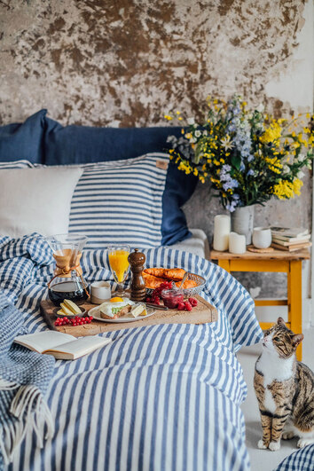 Misty Edge Påslakan 150x210 i färgen Denim Blue på enkelsäng med frukostbricka