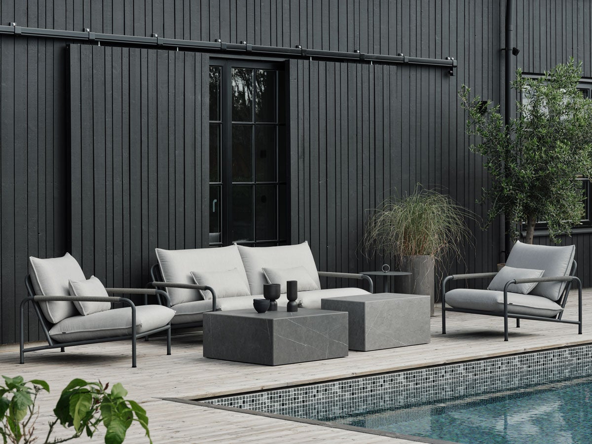 Lerberget Fåtölj och Soffa i grå färg på trädäck framför husfasad