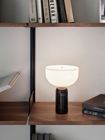 En tänd Kizu portabel lampa i en bokhylla med böcker