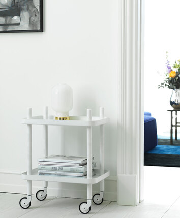 Block Bord Vit med vit bordslampa och tidningar staplade på hög