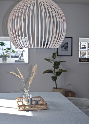 Octo 4240 taklampa Vit i ljust vardagsrum hängande över ett matbord med dekorativ bricka