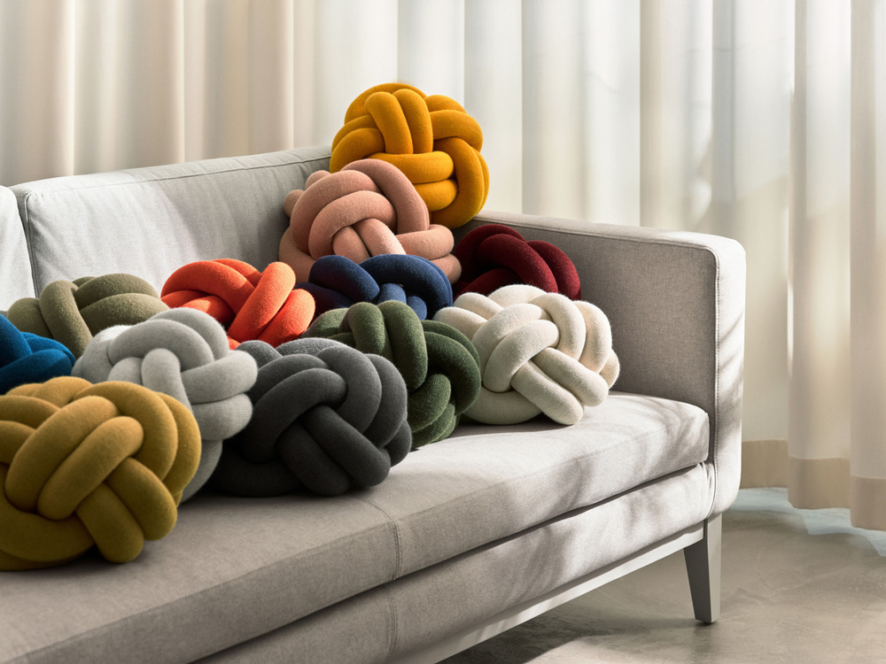 Knot Kudde i flera olika färger på grå soffa