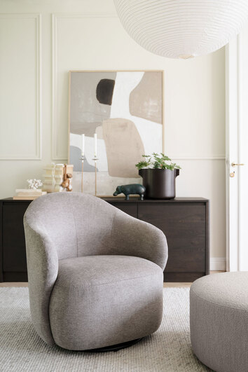 Chapeltown Snurrfåtölj i tyget Brenda 34 Beige framför ett sideboard i vardagsrum