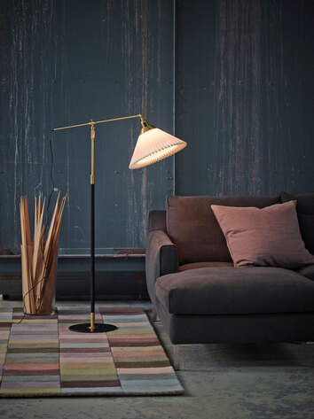 En tänd Le Klint 349 Golvlampa bredvid soffgrupp