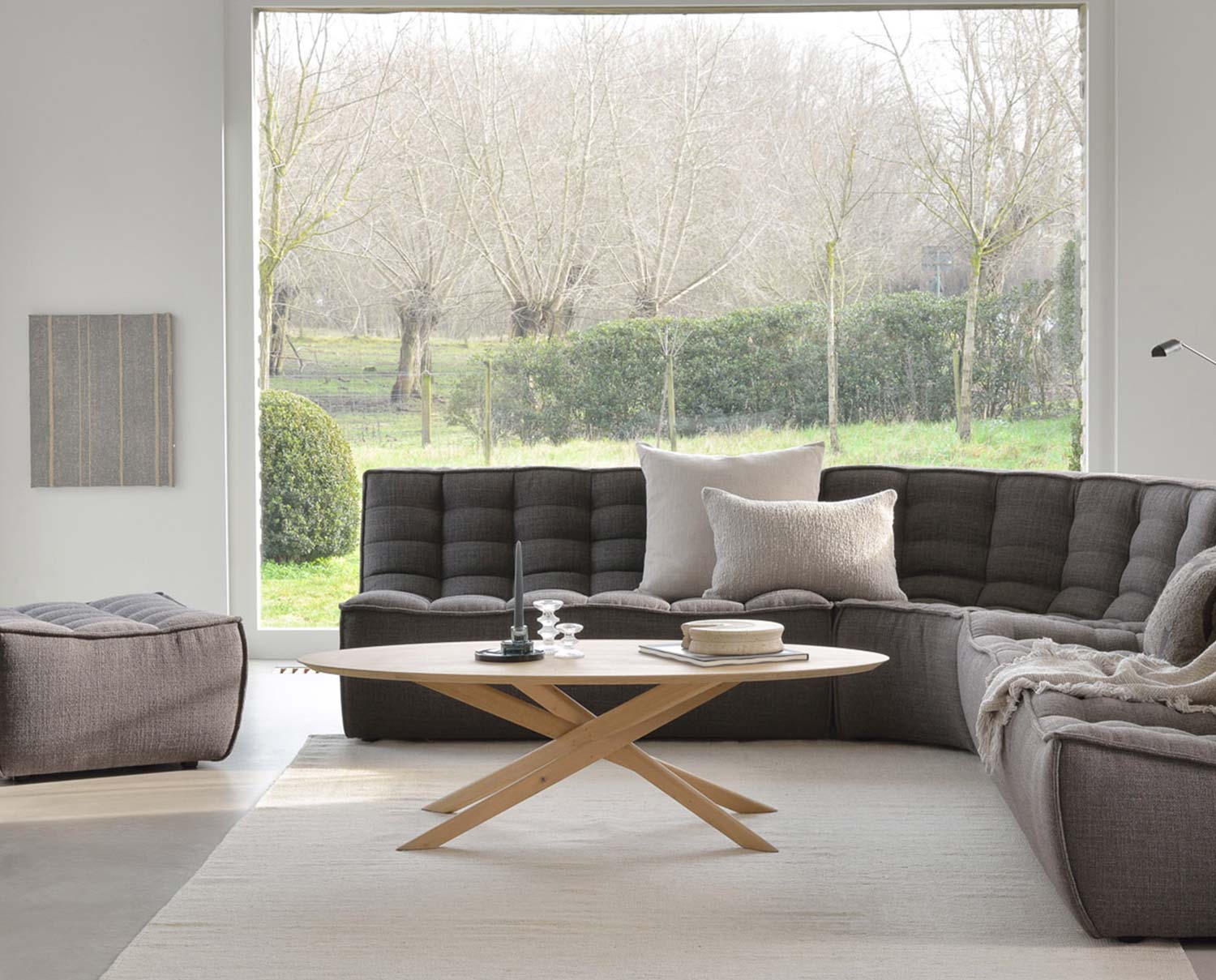 Mikado Soffbord i mitten av N701 Hörnsoffa framför fönster som vetter ut mot träd och buskage