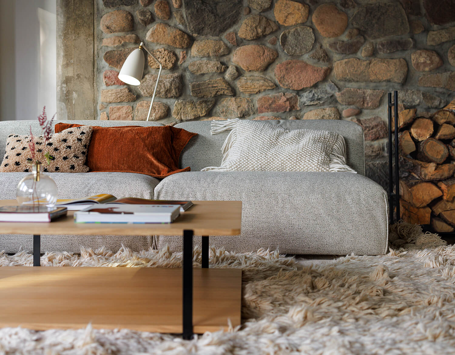 Edda soffa i ett mysigt vardagsrum med fluffig matta och stenvägg i bakgrunden
