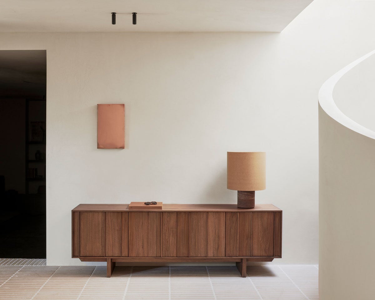 Pillar Sideboard i bredden 220 centimeter dekorerat med en bok och en bordslampa