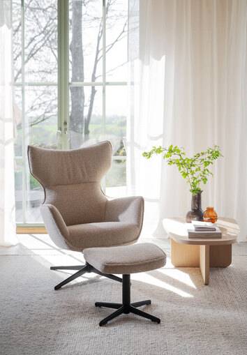 Jenkins Fåtölj och fotpall framför ett fönster med skira gardiner