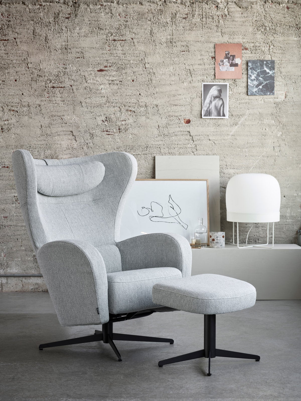 Amanda Fåtölj och Pall i industriell miljö med tavlor med olika motiv på väggarna