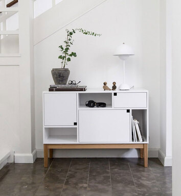 Citti Skåp i färgen Angel White. Skåpet står i hall och är dekorerat med blomma, lampa och inredningsattiraljer.
