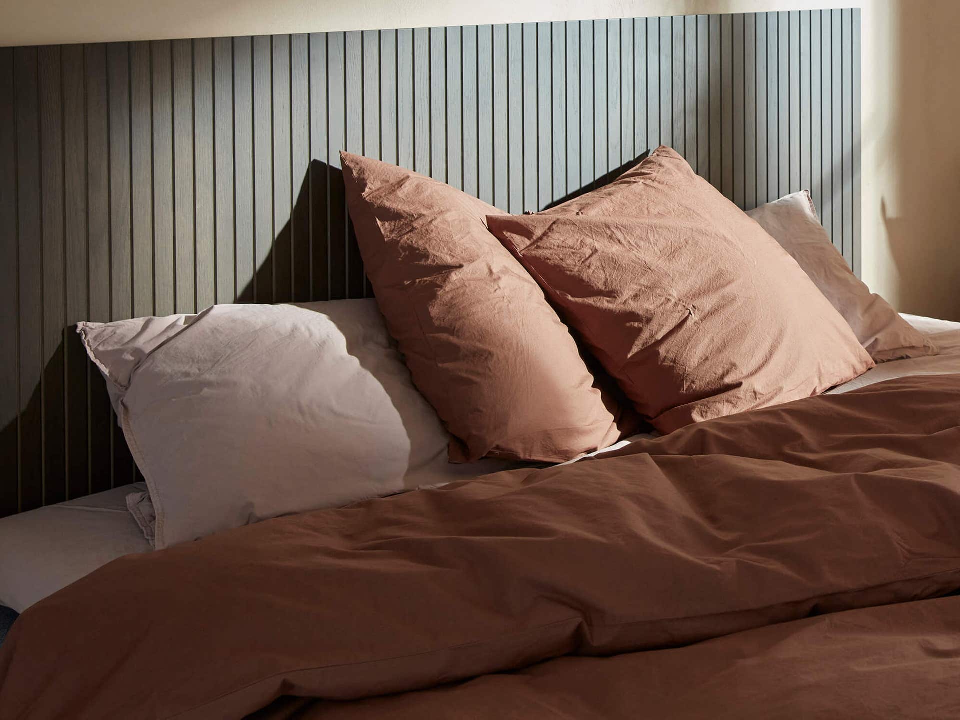 sovrum-tillbehor-header.jpg Handla kuddar och tillbehör hos Tibergs Möbler. Bild på en mysig säng med flera kuddar i varm, röda toner.