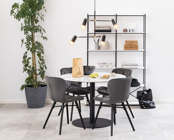 Corby matbord svart fot med stor växt bredvid och bokhylla bakom.