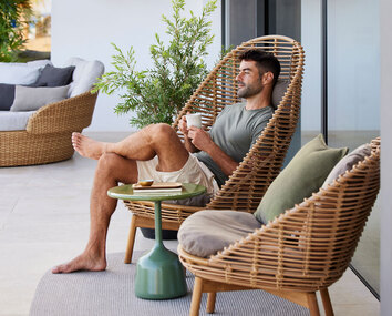 Hive Hög Fåtölj med en avslappnad man sittande med en kopp