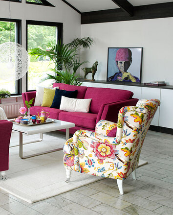 William Large Fåtölj i blommigt tyg bredvid en rosa soffa