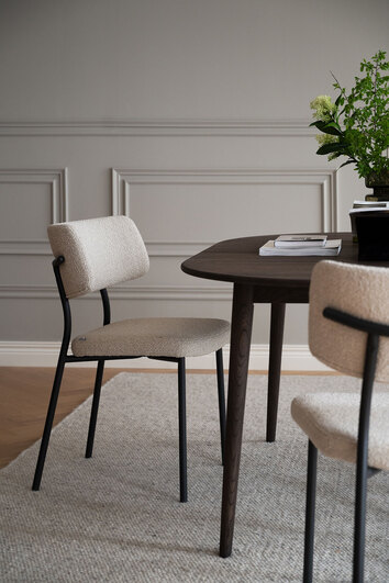Herbster Stol i beige tyg med svarta metallben vid ett brunt matbord i matsal