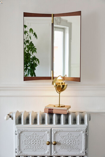 Vanity Väggspegel hängande på vägg ovanför ett element med en guldig bordslampa