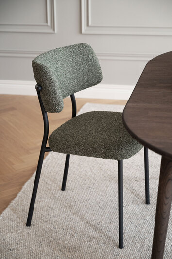 Herbster Stol i grönt tyg med svarta metallben vid brunt matbord i matsal
