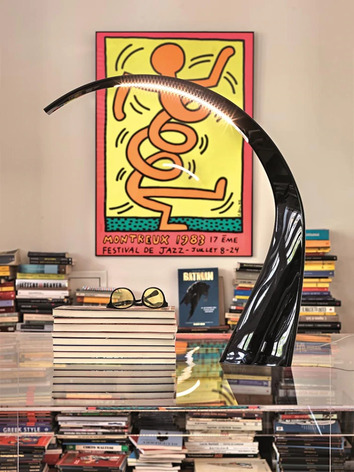 Taj Bordslampa Svart på soffbord med travar av böcker i bakgrunden