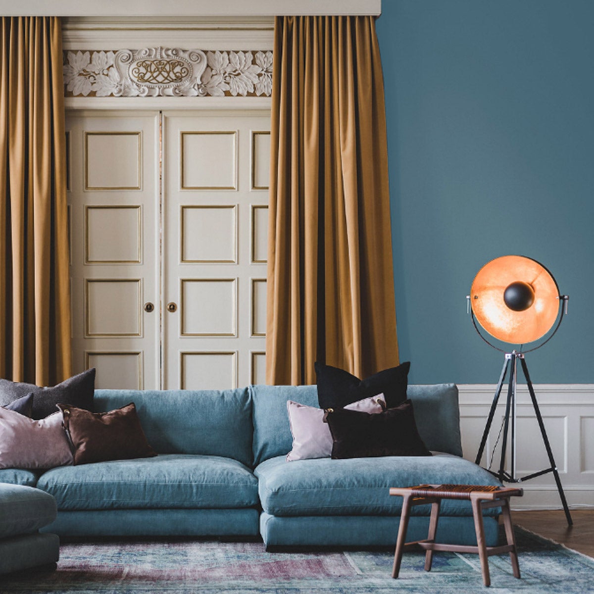 Captain Golvlampa i svart vid en modenr, rymlig, blå divansoffa i en 1800-tals miljö.