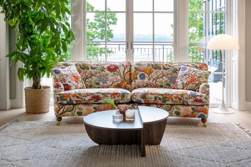 Split Soffbord i rökt ek som står på en beige, mönstrad matta framför en blommig soffa