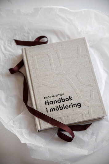 Boken "Handbok i möblering" av Frida Ramstedt på silkespapper