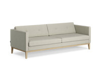 Bilden visar Madison, i tresitsig modell. Soffan är klädd i tyget Retro 06, med knappar i ryggen. Benen är i lackad ek. 