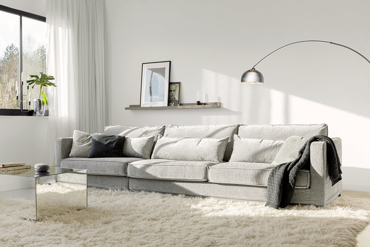 Luna soffa i ett ljust och fräscht vardagsrum med golvlampa, ryamatta och spegelbord