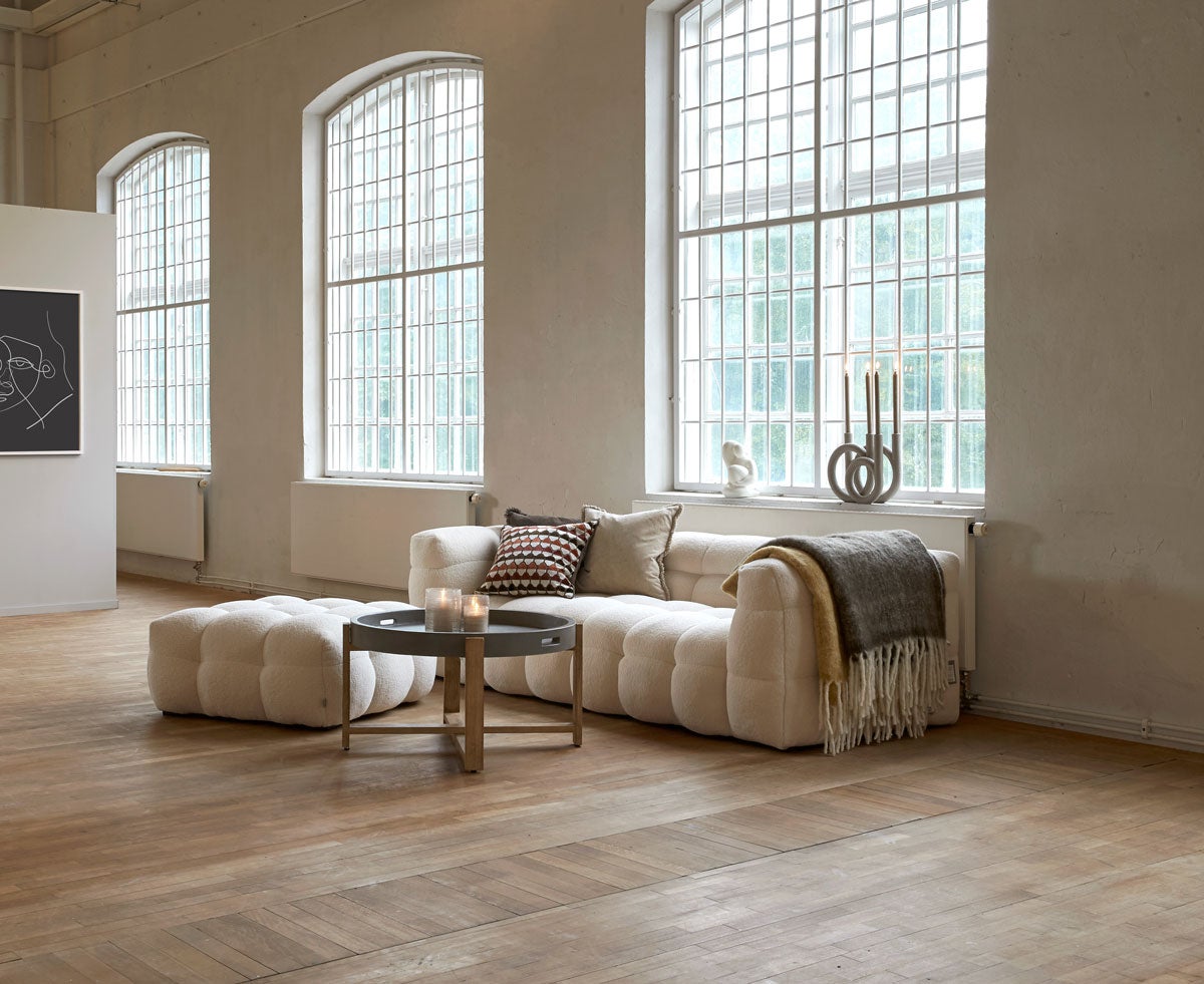 Miljöbild på soffan Kendall. Soffan är klädd i tyget 01 Nature. På bilden visas även pallen Kendall. 