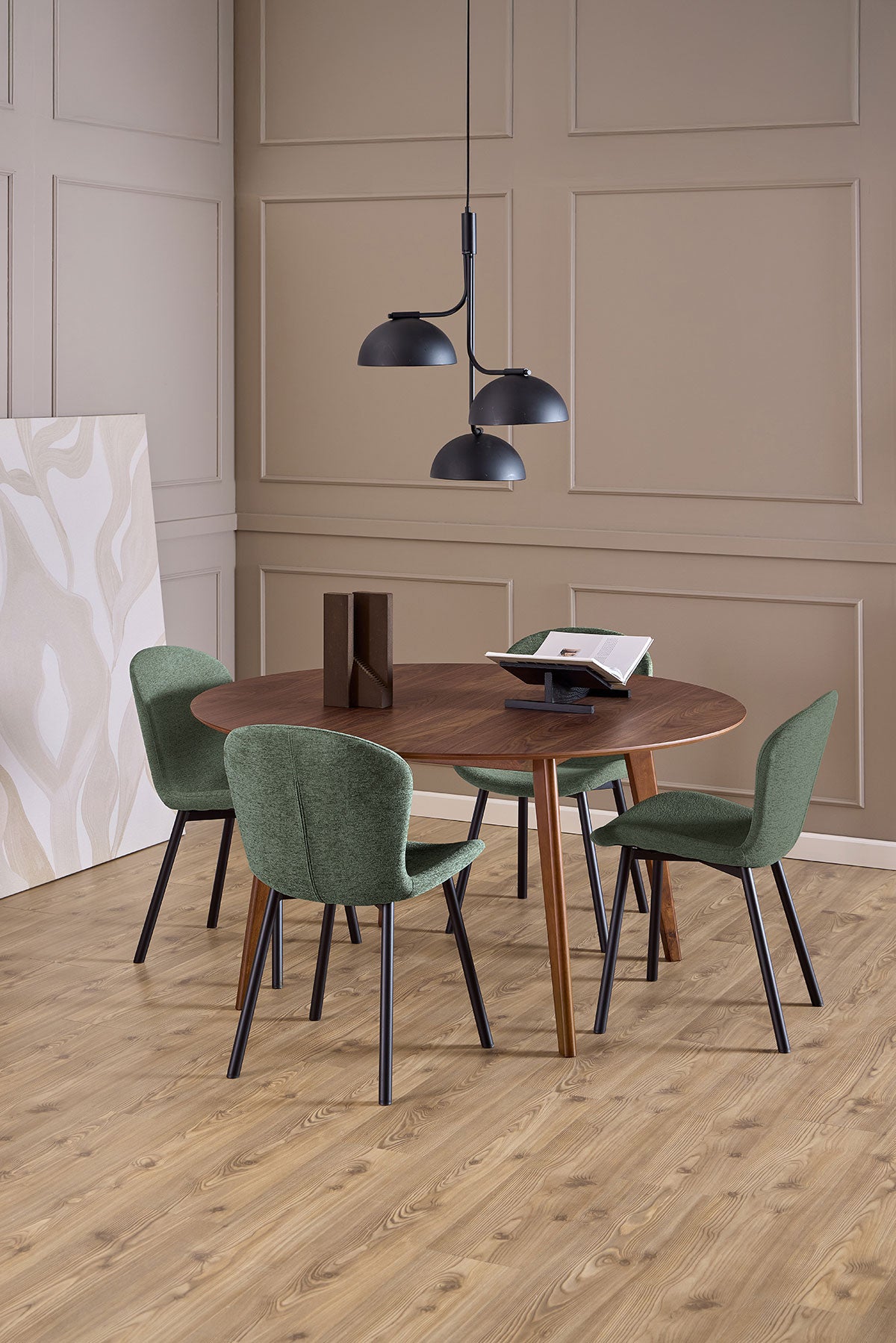Fyra stycken Esra Stol i tyget Apia Grön som står omkring ett runt matbord i mörkt trä
