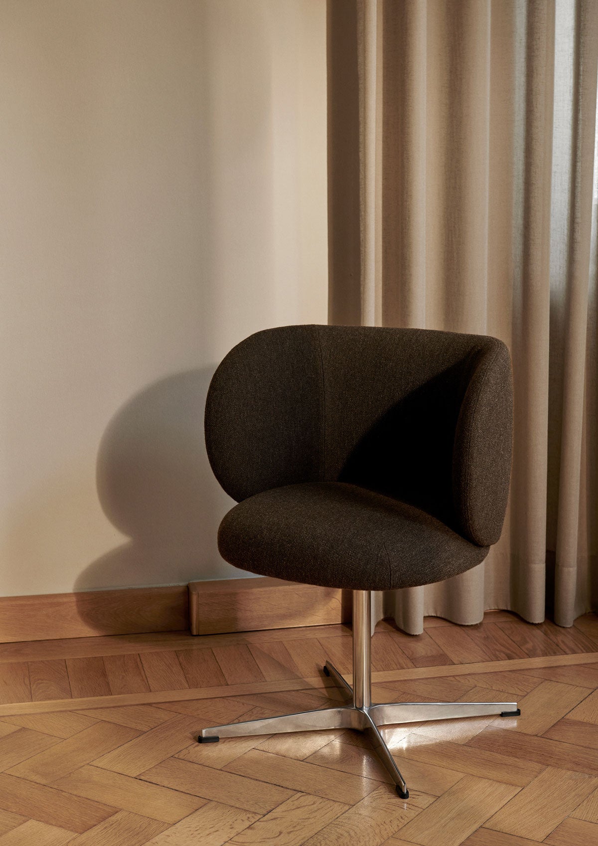 Rico Matstol med snurrfot i tyget Hallingdal Grey/Dark Brown framför fönster med beige gardin
