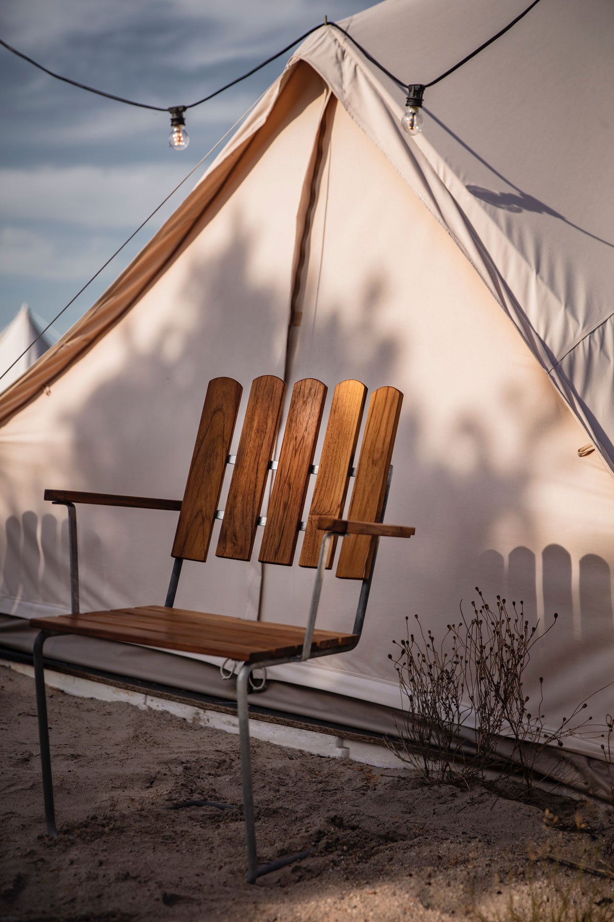 Fåtölj A2 i teak vid vitt tält i solnedgång