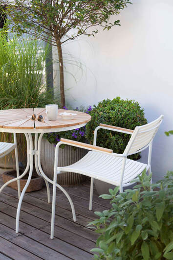 Ellen Cafébord Vit / Teak i solig utomhusmiljö med växter