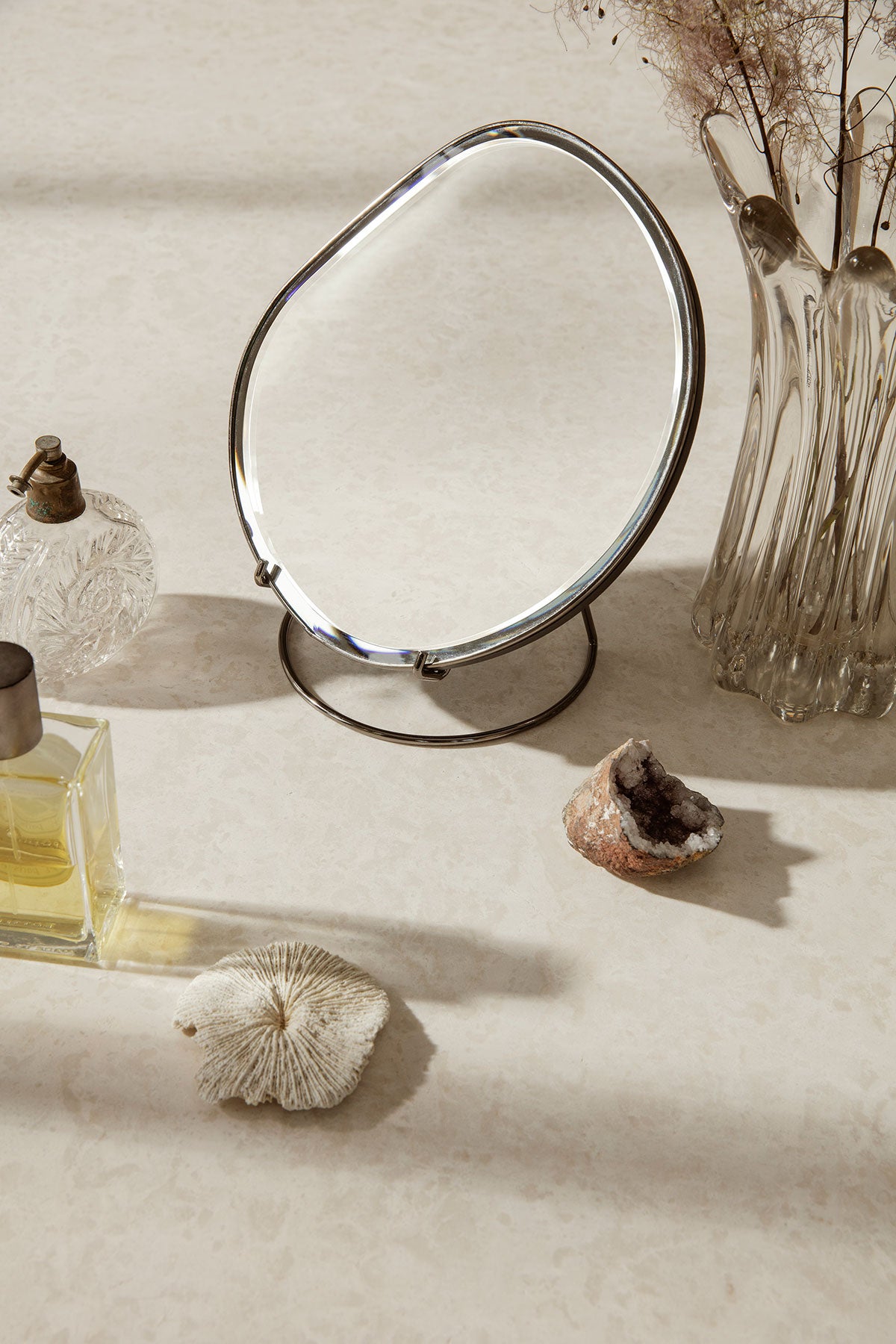 Pond Bordsspegel i utförandet Dark Chrome på sminkbord med parfymer och snäckskal