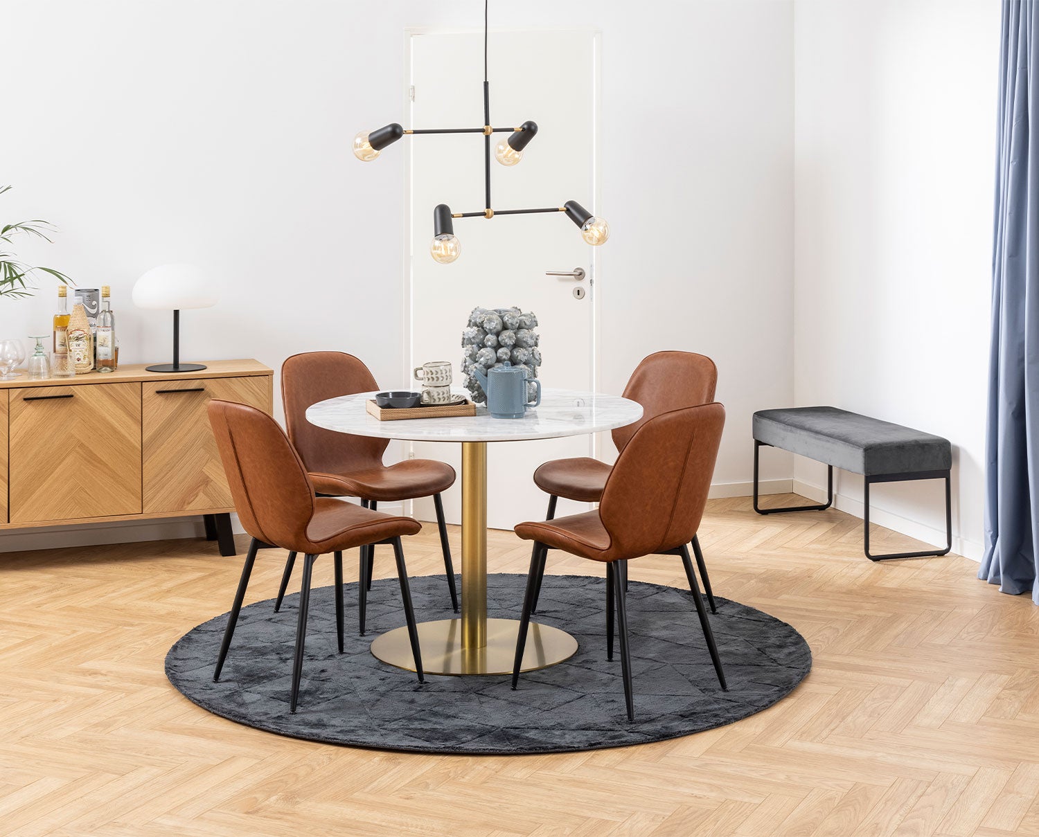 Corby matbord mässingsfot på matta med fyra stolar runt. 