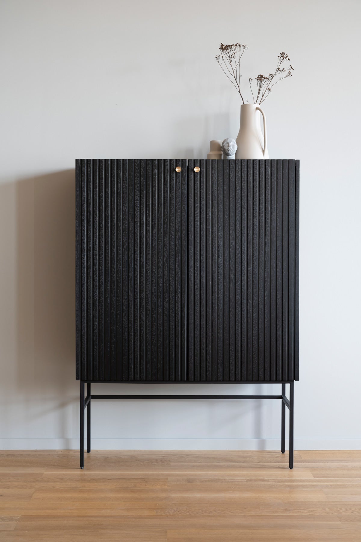 Halifax Skåp i svartlackad ek med en vas med kvistar