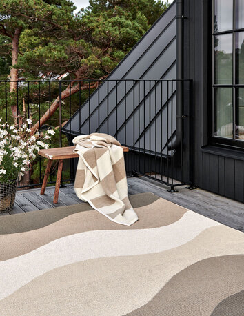 Bob Pläd i färgen Mud / Vanilla på bänk utomhus