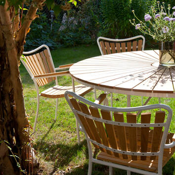 Ellen Trädgårdsstol Vit/Teak runt Ellen Trädgårdsbord i trädgård med grön gräsmatta