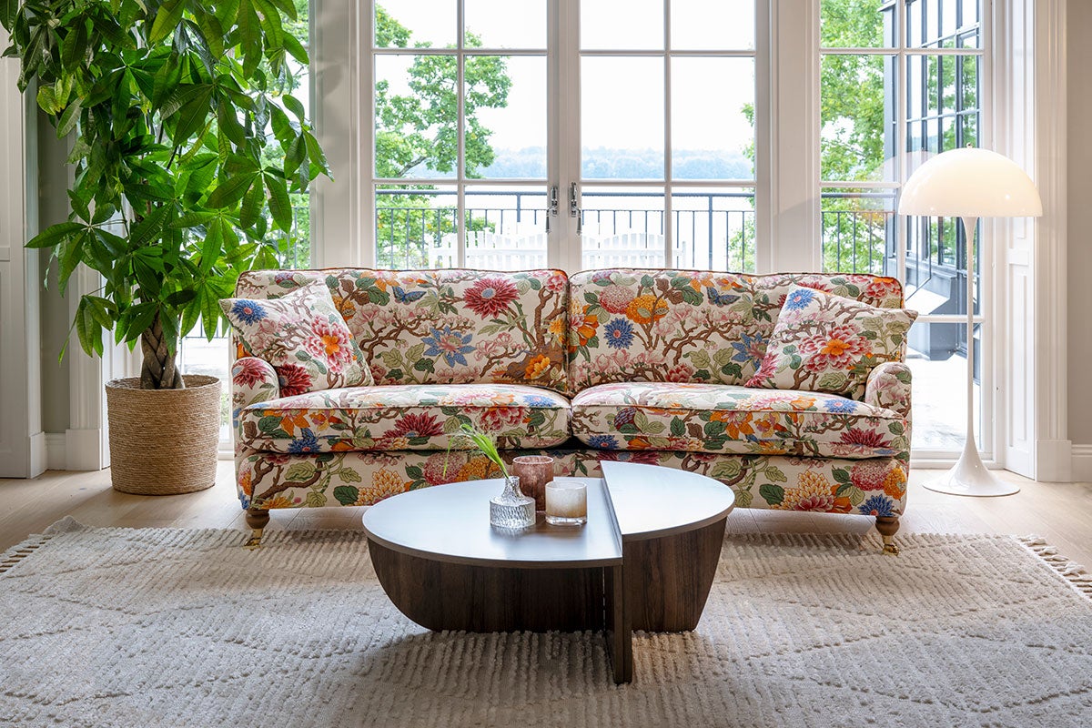 Split Soffbord i rökt ek som står på en beige, mönstrad matta framför en blommig soffa